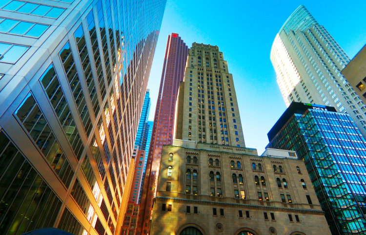 The sun casts a striking reflection against tightly packed city skyscrapers