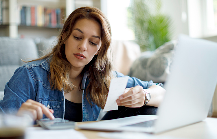 Femme assise devant un ordinateur et préparant un budget.